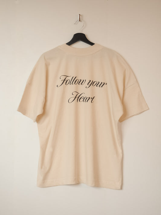 a cream white oversized t-shirt with a black back print saying Follow your Heart.