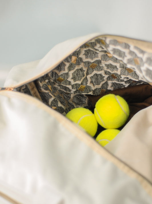 A close up picture of the flower pattern golden lining. You can see Tennis Balls laying inside the weekender.
